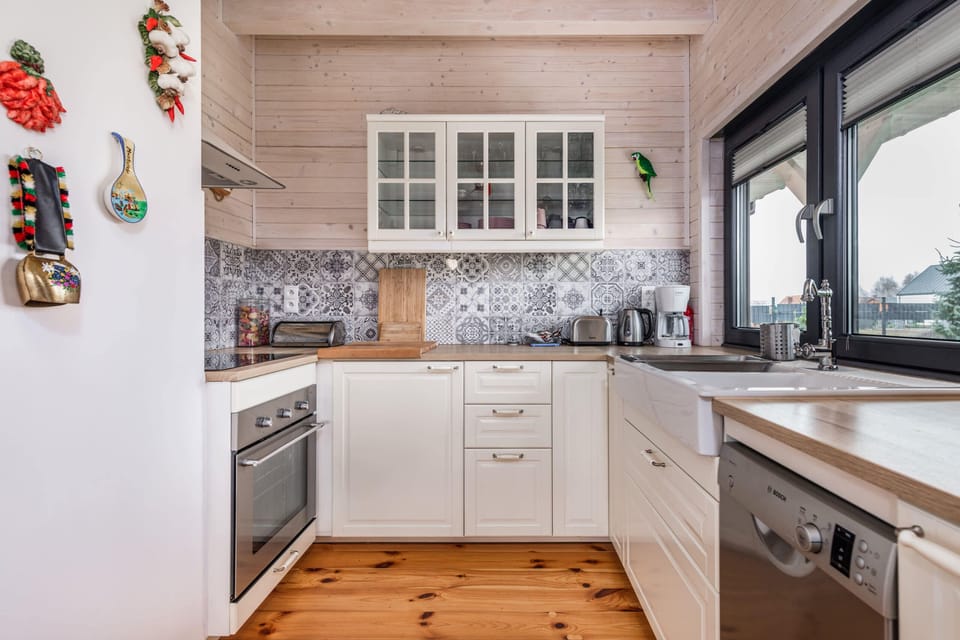 A stunning kitchen design featuring white cabinets with brass handles, a pristine white tiled backsplash, and open shelving for an organized and stylish look. Ideal for cooking enthusiasts seeking both functionality and aesthetics.