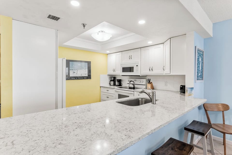 Your fully equipped kitchen features modern appliances, gleaming countertops, and cheerful coastal colors—perfect for preparing morning coffee or a home-cooked meal during your stay.