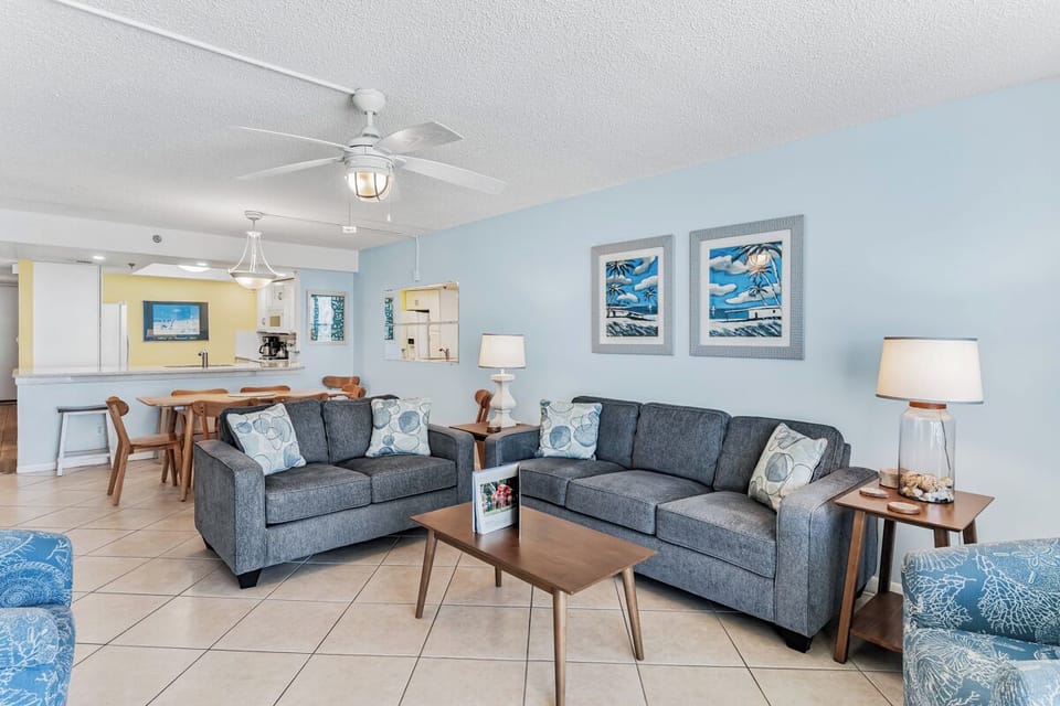Unwind in your inviting living space with coastal charm, featuring plush seating, cheerful blues, and an open flow to the dining area and kitchen—your home away from home.