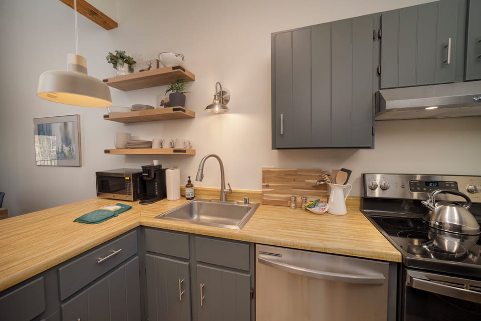 Your fully-equipped kitchen awaits with warm wood counters, modern appliances, and charming open shelving for all your culinary adventures.