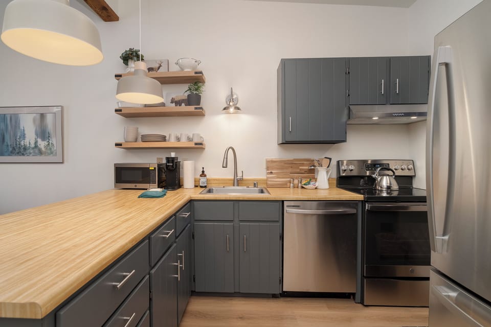 Your modern kitchen features sleek gray cabinets, butcher block counters, and stainless steel appliances, perfect for preparing meals during your stay.