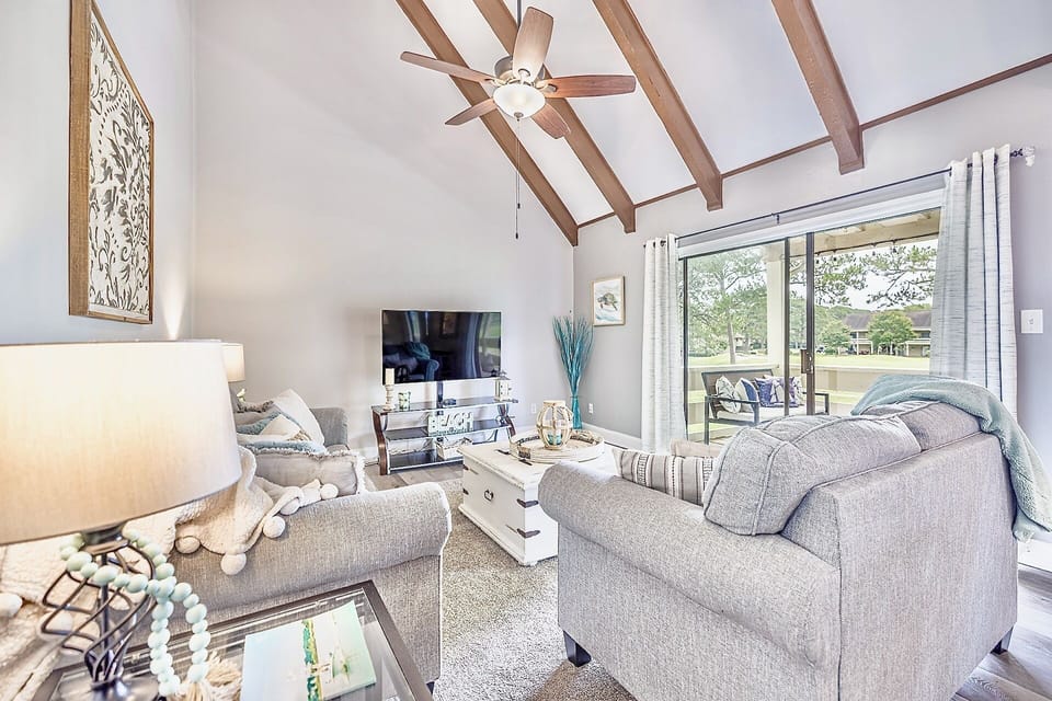 The open concept living area with 2 story vaulted ceilings offer double sliding glass doors with access to the balcony overlooking the golf course.