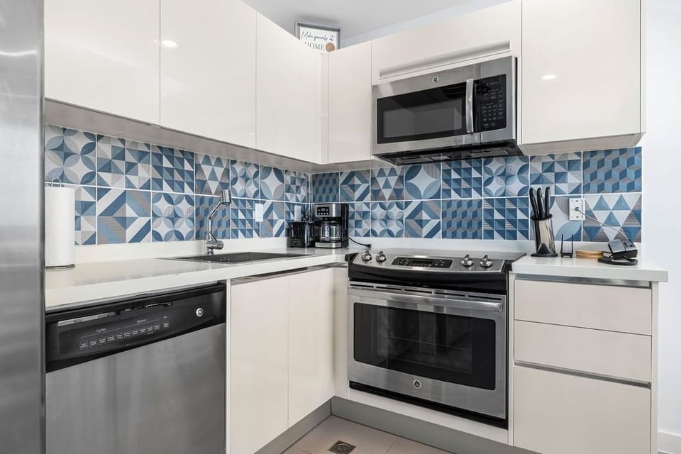 Your stylishly equipped kitchen features sleek white cabinetry, vibrant geometric tile backsplash, and modern stainless-steel appliances ready for meal prep during your stay.