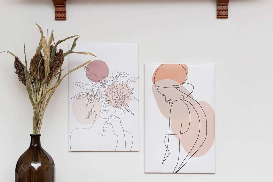 Close-up of an ornate vase with flowers and paintings hanging on the wall.