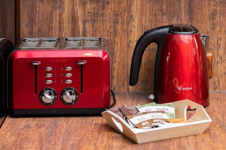 Focus on a red toaster and kettle on a wooden countertop, creating a bold contrast with the rustic kitchen setting.
