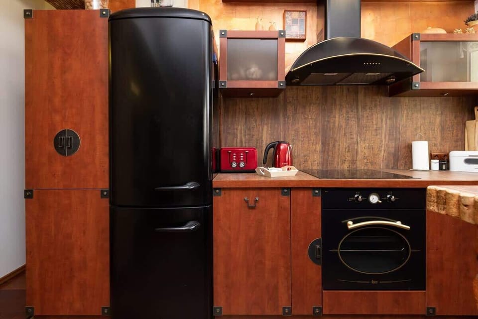 Kitchen showcasing wooden cabinets, a black refrigerator, and modern appliances, including a red kettle and toaster.