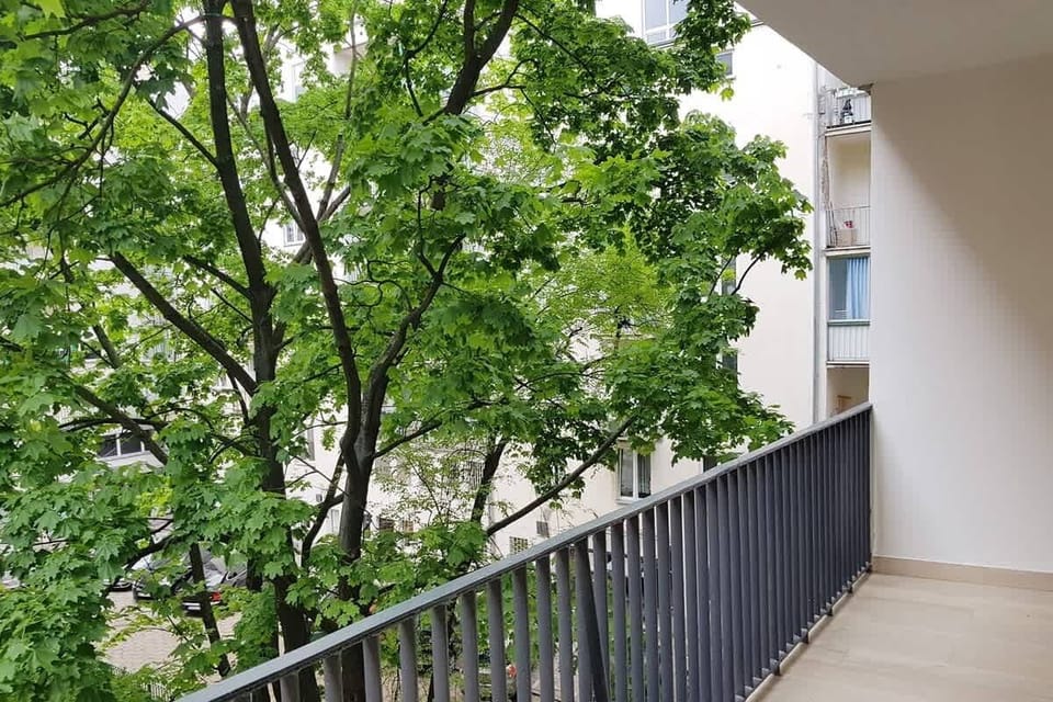 Private balcony with seating arrangements, offering views of the surrounding cityscape and ample sunlight.