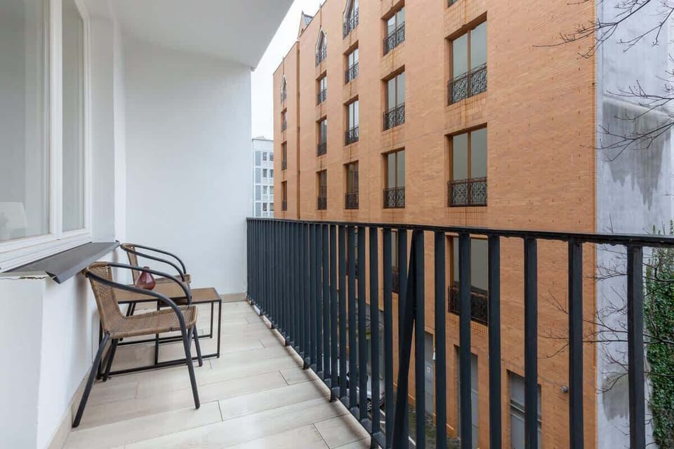 Private balcony with seating arrangements, offering views of the surrounding cityscape and ample sunlight.