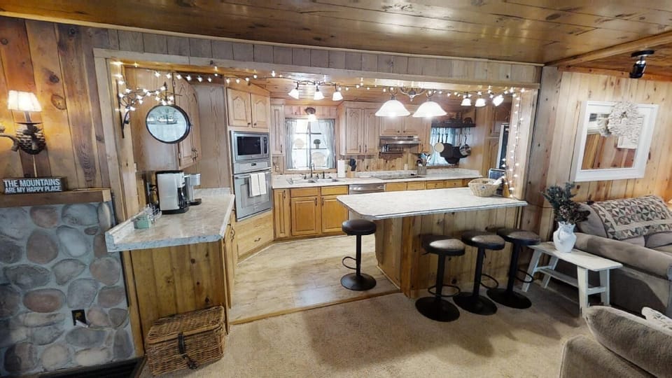 Your rustic mountain retreat features a fully-equipped kitchen with a spacious island, cozy fireplace, and open living space—perfect for gathering after a day of adventure.