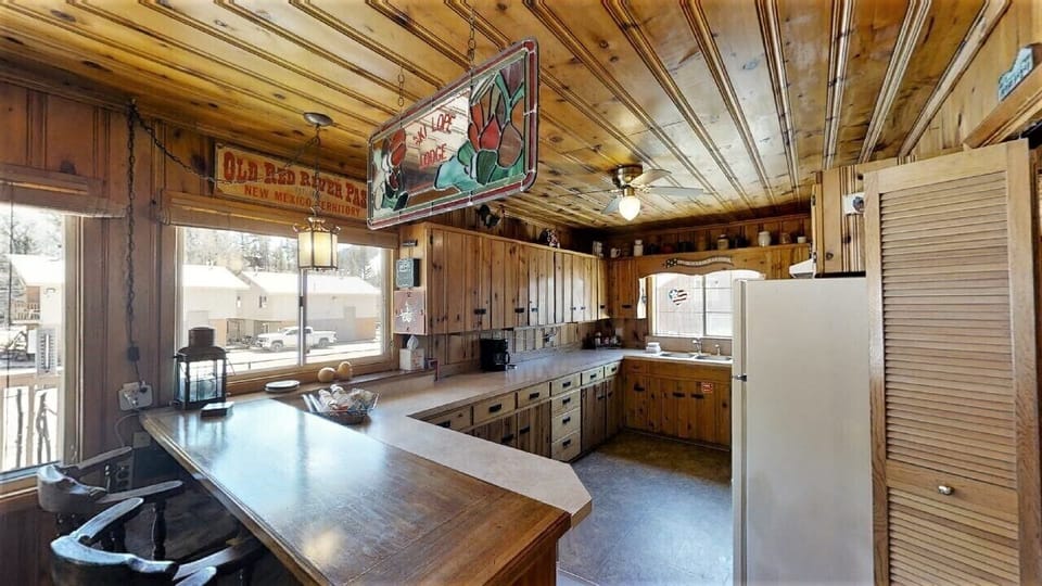 Step into a cozy rustic kitchen where wood-paneled walls and exposed beams create a charming cabin atmosphere. Enjoy ample counter space, vintage-inspired touches, and all the essentials for your mountain getaway meals.