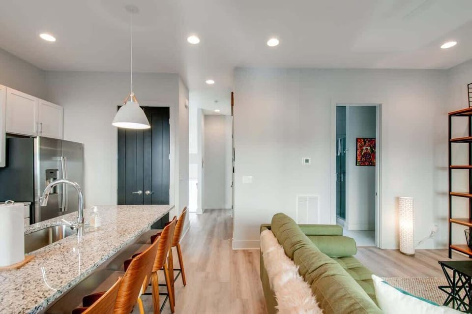 The green sofa and kitchen island with bar stools create the perfect gathering spot for a house that sleeps 12, keeping the group connected over breakfast or pre-game drinks