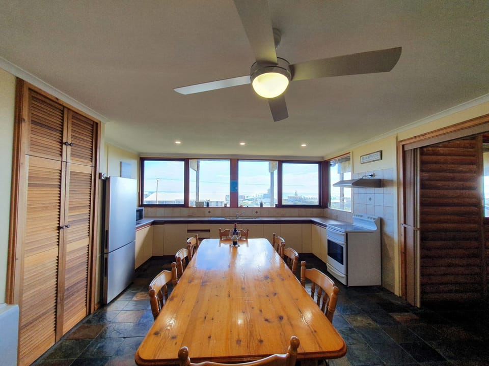 Includes a large front deck with sea views, a pergola-covered dining space, fire pit, paved and grassed backyard zones, outdoor shower, and a dedicated surfboard rack.