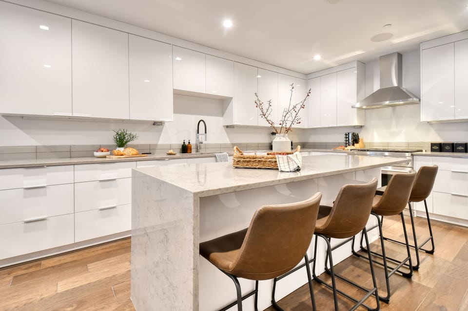 Sleek kitchen features an island with marble countertop and barstool seating.