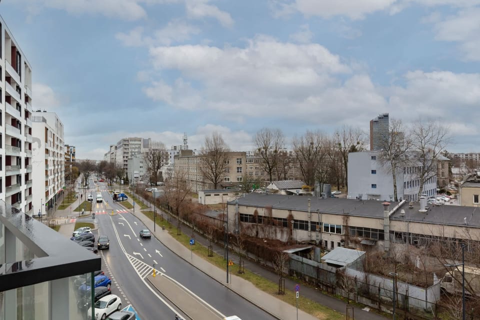 View from the balcony over the surrounding area. View of street and distant buildings.
