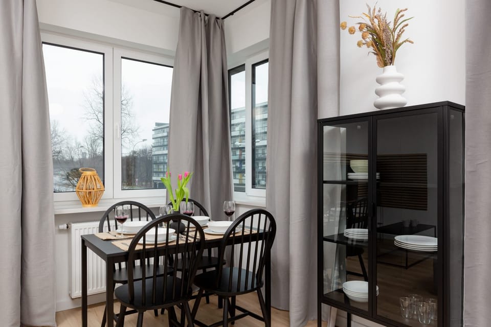 Dining area of the room with display cabinet with kitchenware. The large windows let in plenty of natural light which emphasises the cosiness of the room.