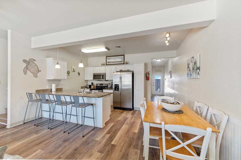 Your bright, open kitchen flows seamlessly into the dining area, perfect for cooking meals together and gathering around the warm wood table.
