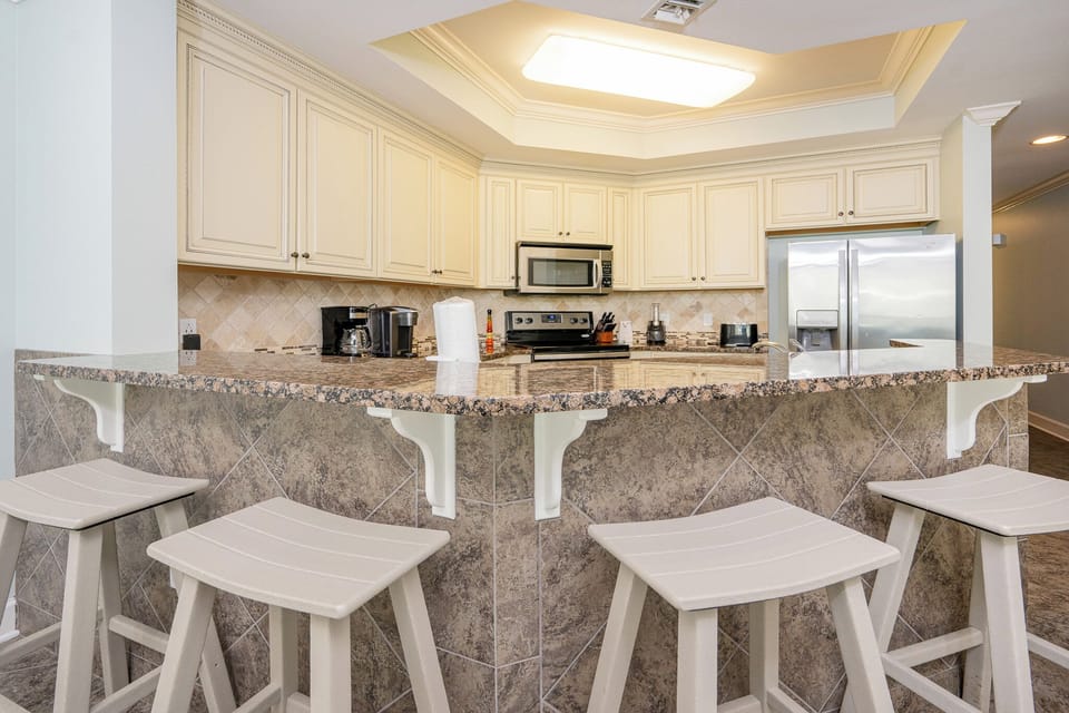 Kitchen with granite countertops, stainless appliances, coffee station, and cozy bar seating for a casual dining experience