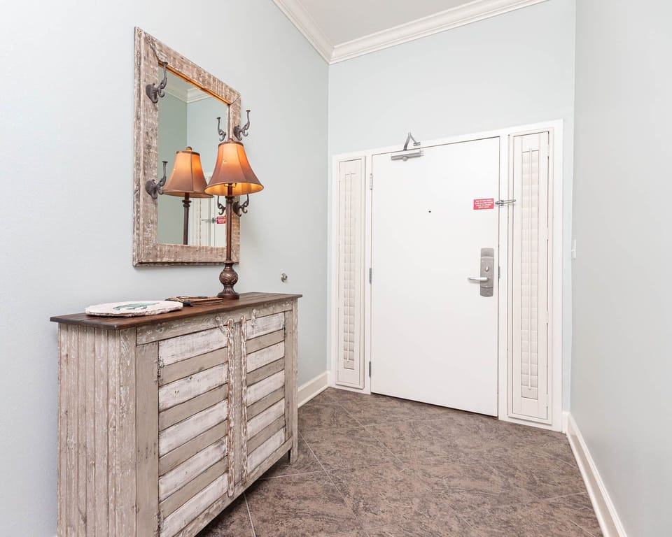 Charming entryway featuring a rustic console table, warm lamps, and a stylish mirror against soft blue walls