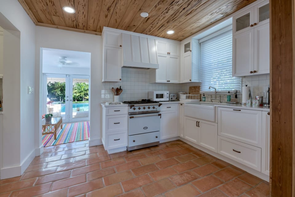 Gorgeous newly upgraded kitchen with stainless steel double door refrigerator, white Farmhouse style gas range, stove, Nespresso Vertuo 3 coffee maker, toaster and new white counter tops.