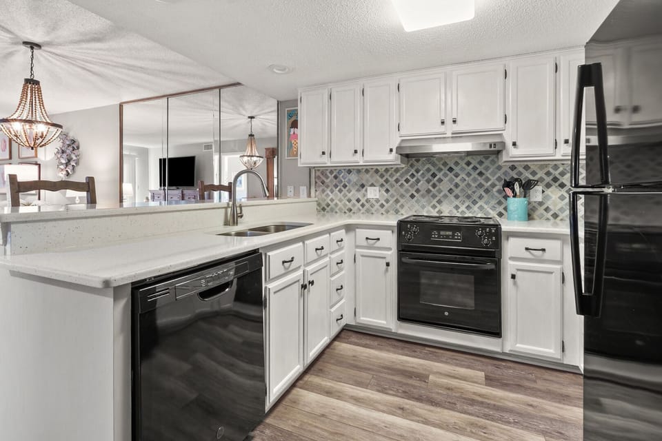 Kitchen with white cabinetry, black appliances and an island sink at Coastal Shores C2, Ocean Drive