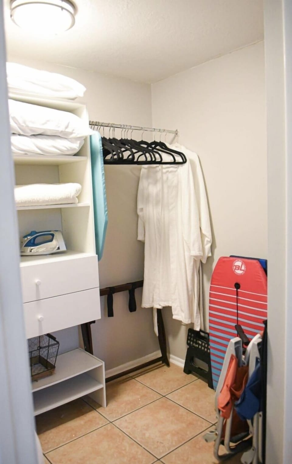 Closet with ironing board and beach accessories.
