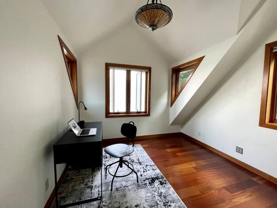 Office has vaulted ceiling and windows that look onto ocean and garden