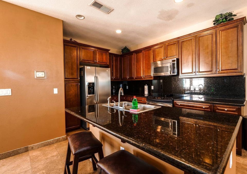 The upstairs kitchen is fully stocked and opens to a huge patio overlooking the golf course, featuring a BBQ for entertaining .