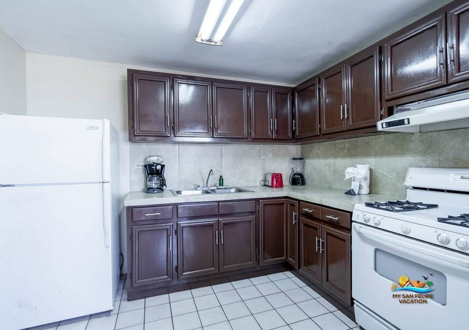 This well-stocked kitchen features a full-size refrigerator with freezer, 4-burner stove, oven, microwave, and coffee maker — plus dishes for 10, all just steps from the beach.