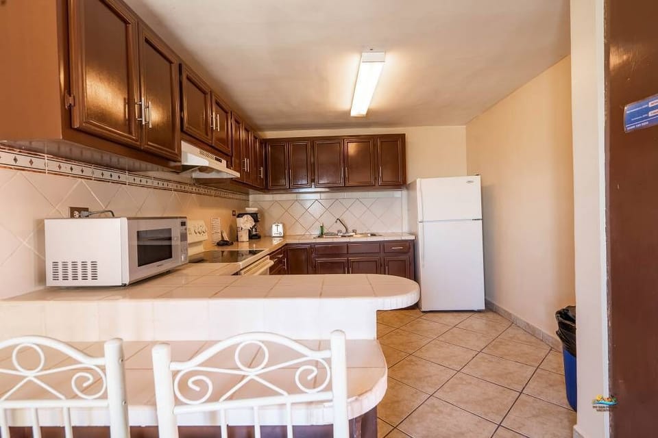 This open kitchen has a 4-burner stove with oven, microwave, full-size fridge, coffee maker, and dishes for 10 — just steps from the beach
