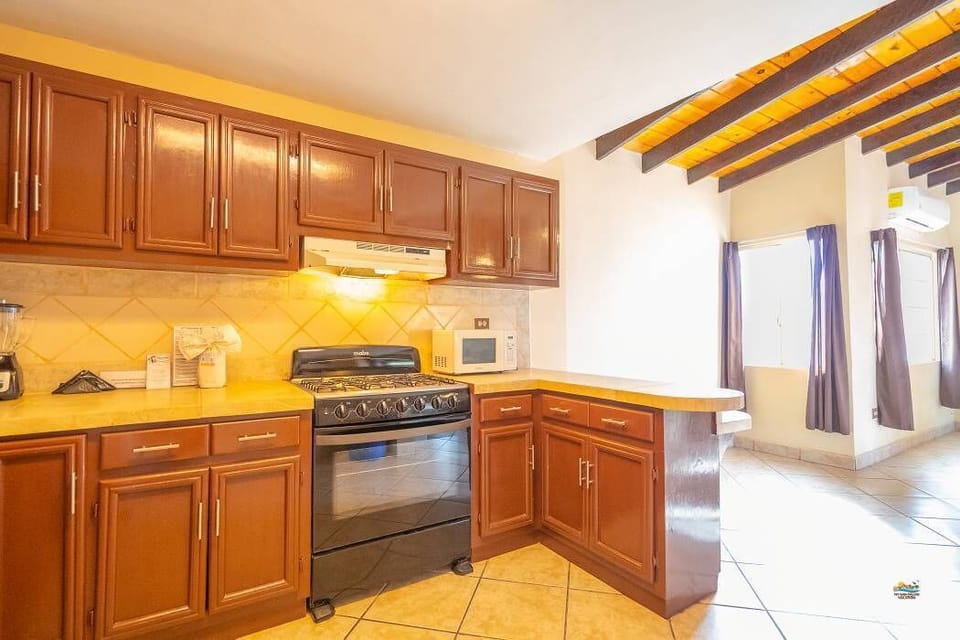 The well-equipped kitchen includes a 4-burner stove with oven, full-sized refrigerator, microwave, and coffee maker — just steps from the beach and a short walk to the Malecon
