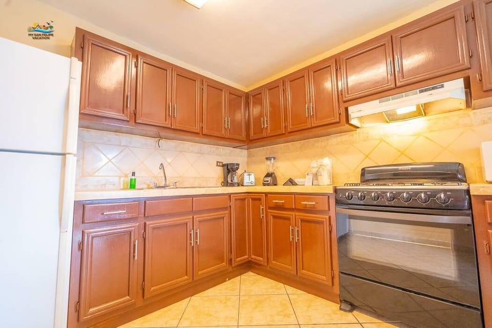 The well-equipped kitchen includes a full-sized refrigerator, 4-burner stove, oven, microwave, and coffee maker — just steps from the beach and a short walk to the Malecon.