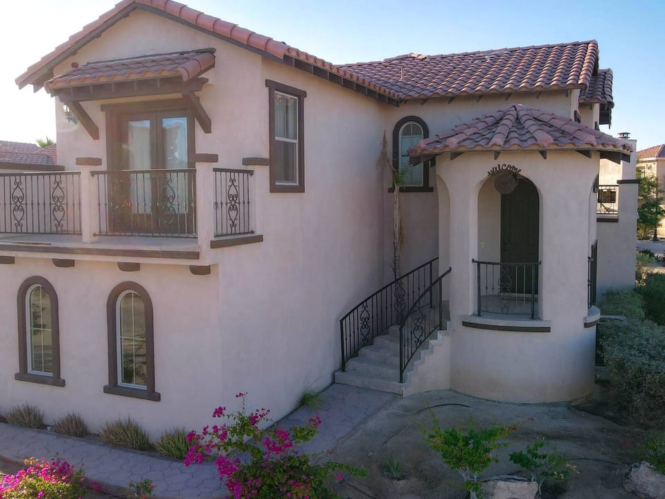 The front facade features traditional stucco architecture, a private entrance, and paved driveway parking, set within the secure gates of the El Dorado Ranch community.