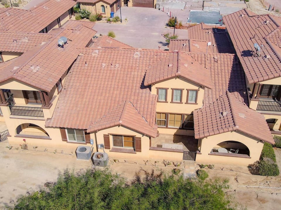 This aerial shot from the back shows the condo's position near community amenities, golf course views, and the surrounding desert landscape of El Dorado Ranch.