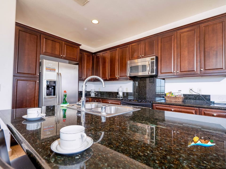 Fully equipped kitchen with refrigerator, stove, microwave, dishwasher, and breakfast bar .