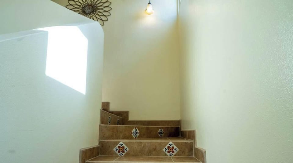 Stairs lead to second floor bedrooms and rooftop access. The main level has the kitchen, living room, dining area, and porch.