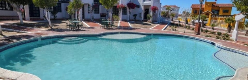 The La Hacienda community features a large swimming pool surrounded by trees, with lounge chairs and a BBQ grill nearby