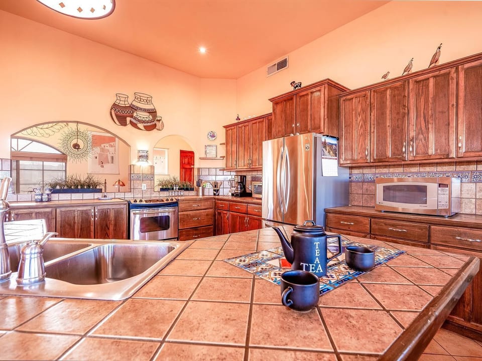 The kitchen at Casa Zur Heide features an island with bar stool seating, ample granite counter space, and a window overlooking the backyard — making meal prep and casual dining easy in this 3-bedroom vacation home .