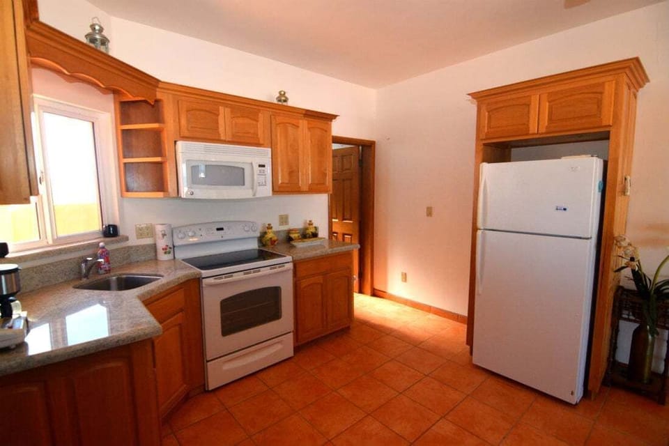 The upstairs kitchen in Condo B features a snack bar with nine bar stools, modern appliances, and flows into the dining and living areas — part of this 4‑bedroom, 4‑bath beach‑side villa .