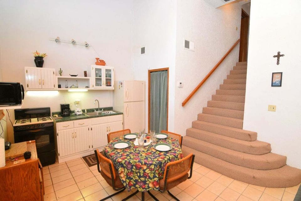 The kitchen area at Casa Rubio del Mar features a full-size refrigerator, microwave, essential kitchenware, and a cozy dining table for two .