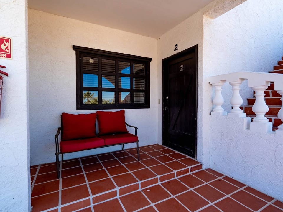 The gated community entrance requires an electronic access card for entry, located off Highway 5 approximately 9 km south of downtown San Felipe. A paved driveway leads to this two-story building.