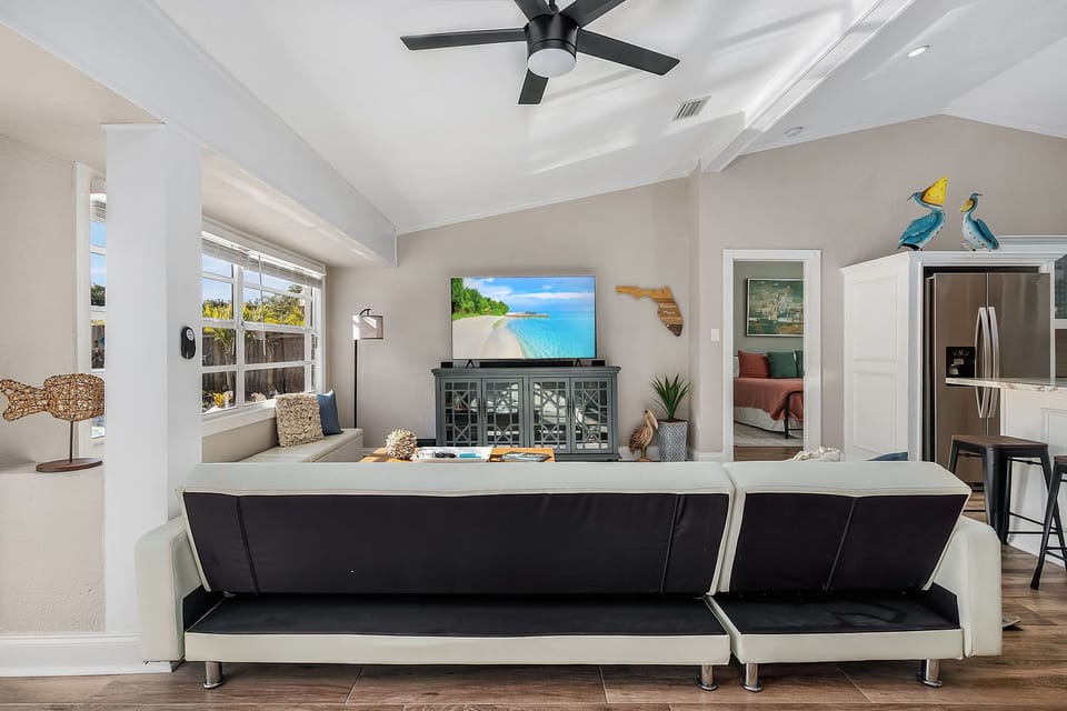Livingroom with big screen TV just off the kitchen and window view of pool.