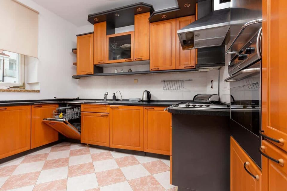 A modern kitchen with polished wooden cabinetry, black countertops, and ample cooking space, ideal for a functional yet aesthetic design.