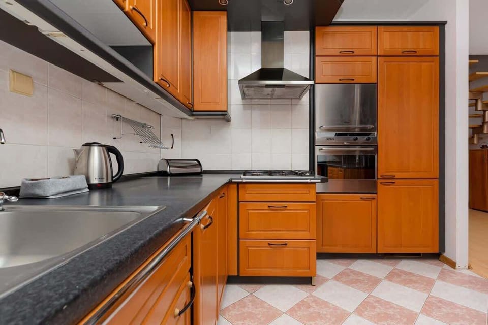 A close-up of a kitchen corner featuring light brown cabinets, a built-in oven, and vibrant tiled flooring.