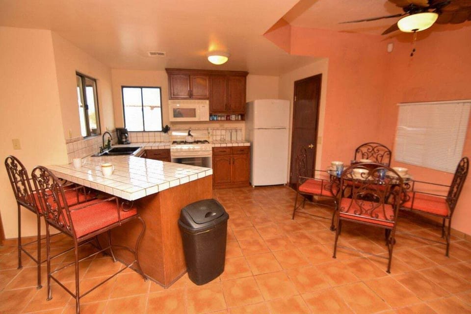 U-shaped kitchen with granite countertops, double sinks, gas stove, and full-size fridge. Breakfast bar with high-top seating connects to the living room.