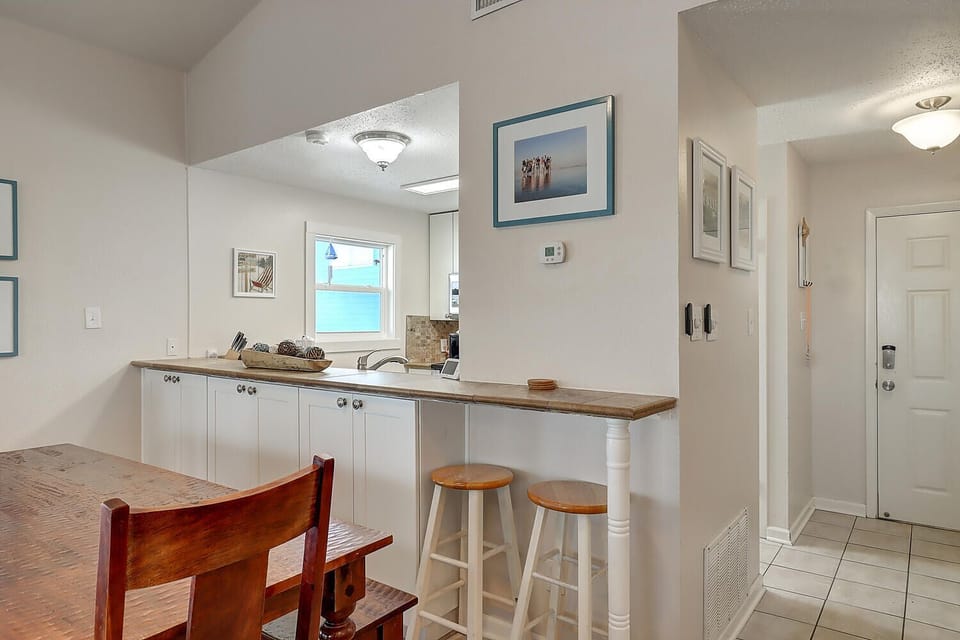 Your open kitchen invites morning coffee at the breakfast bar while ocean views peek through the window.
