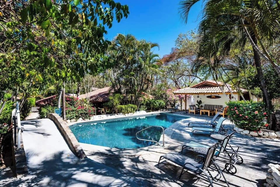 Shared outdoor spaces include a tropical pool and cozy bungalow area, offering a safe and relaxing environment for families or groups staying in Tamarindo.