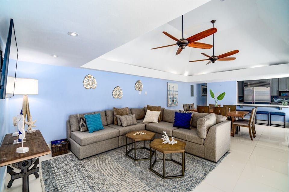 The spacious and comfy living room with flat screen TV, cold AC, with the kitchen in the background.