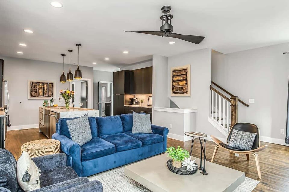 Gather around the vibrant blue sofa in a spacious open-concept living room designed for comfort and connection.