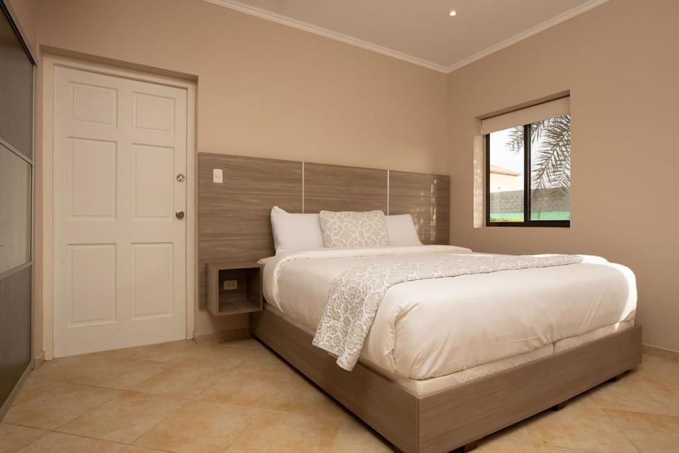 This bedroom features a minimalist design, a queen size bed, & airconditioned