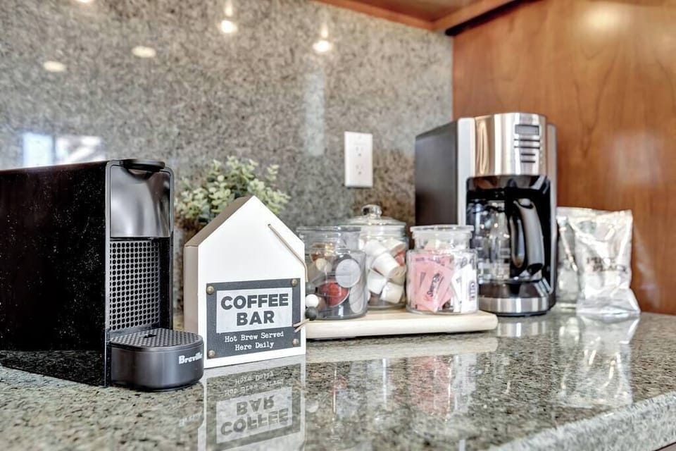 Modern coffee bar setup with a drip coffee maker and espresso machine on a granite countertop.